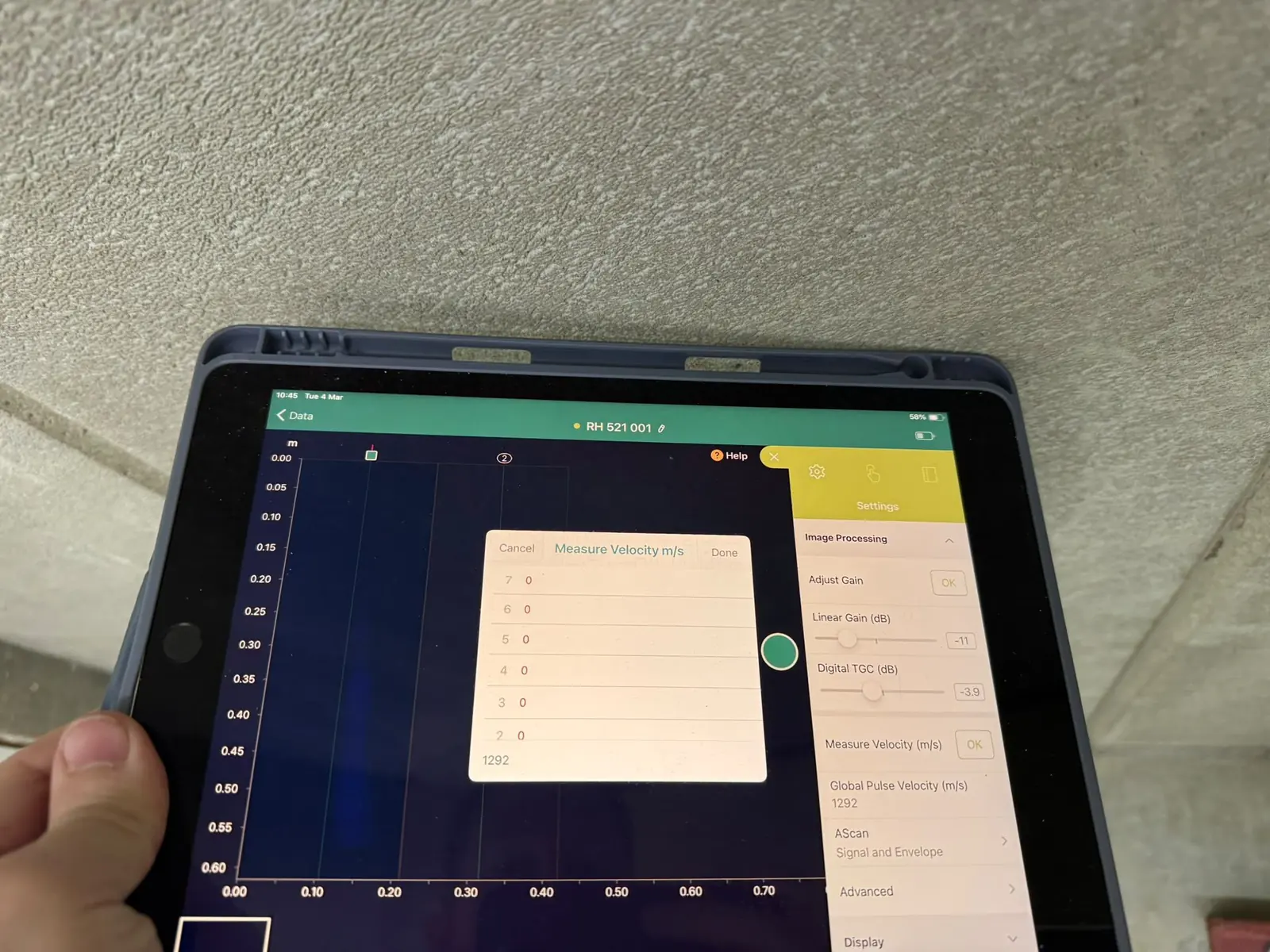Ultrasonic test data on a tablet beneath a concrete soffit